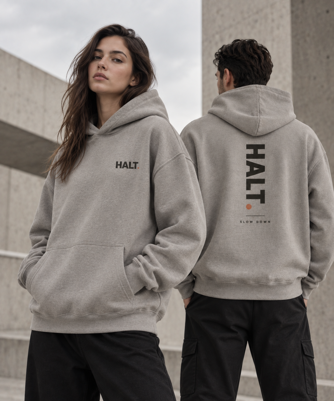 HALT. Slow Down oversized heather grey hoodie worn by two models, front chest logo and large vertical back print, unisex heavyweight streetwear pullover