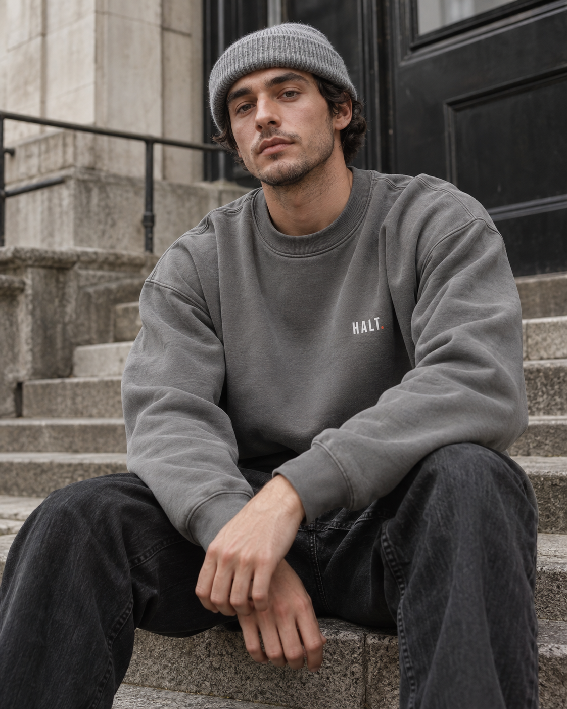 Man wearing the HALT. Slow Crewneck in stone grey, a heavyweight crewneck sweatshirt with left-chest logo, styled with a beanie and jeans